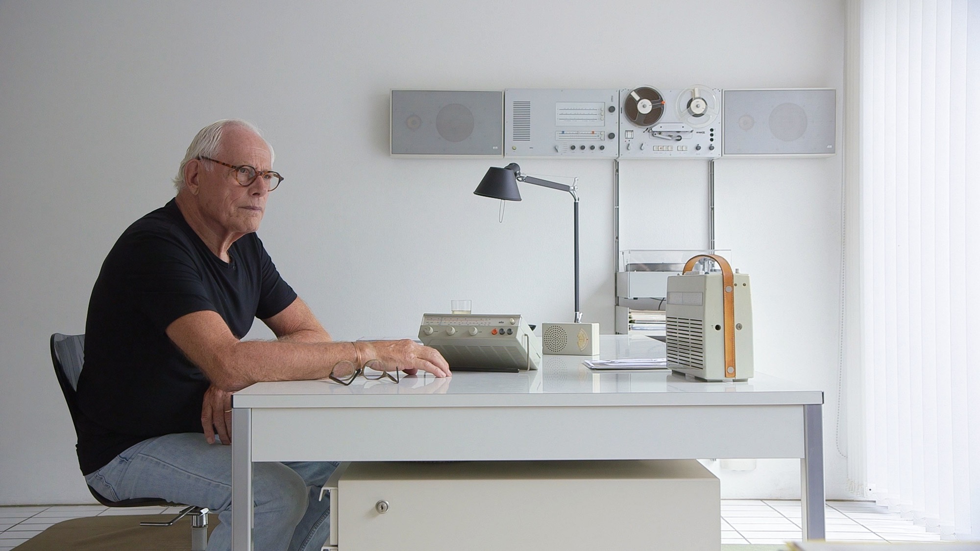 Portrait of Dieter Rams at his desk at home surrounded by some of his designs